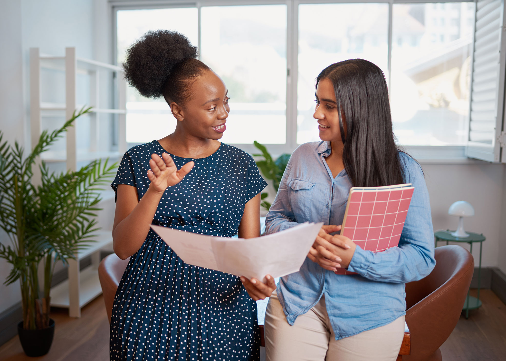 "Two professionals reviewing documents and discussing plans in an office setting."