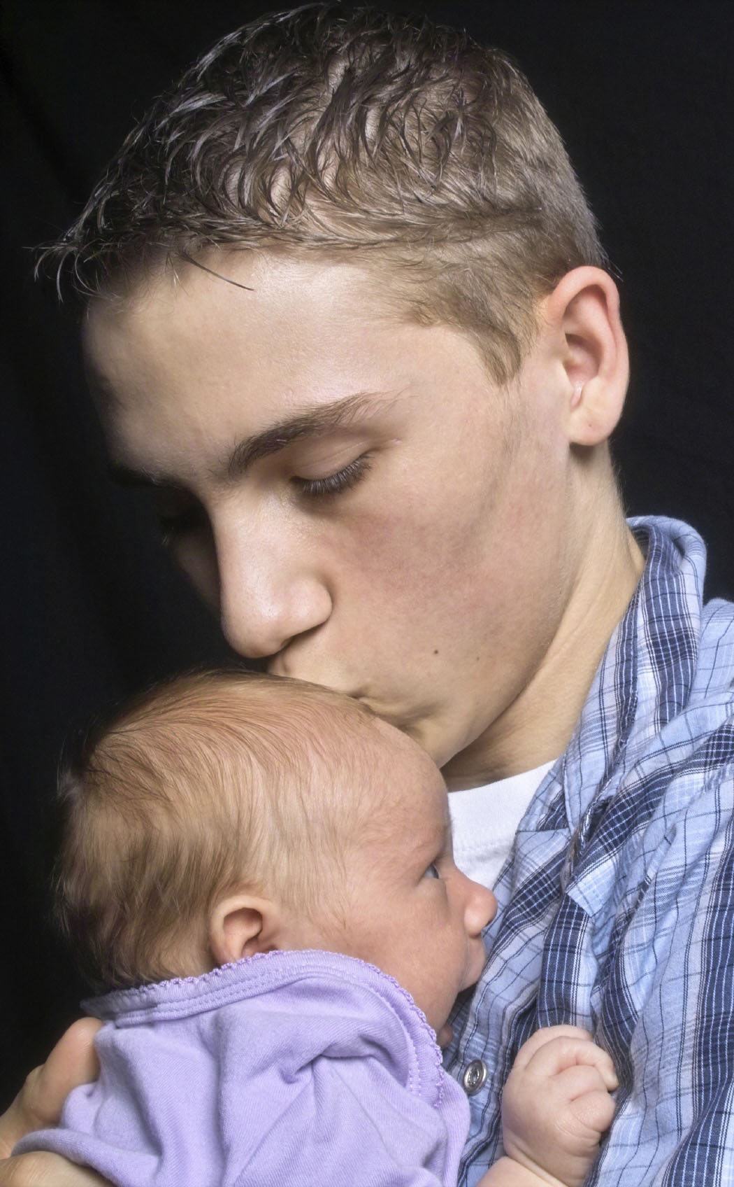 "Father holding and kissing baby's head"