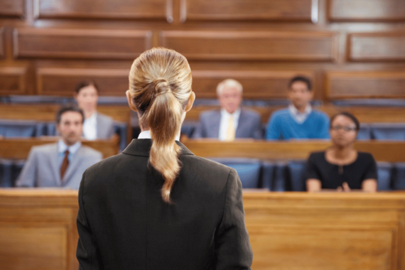 Courtroom scene with a person addressing a seated audience.